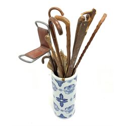 A blue and white stick stand, containing various wooden walking sticks, to include thornwood examples, and a shooting stick with leather seat. 