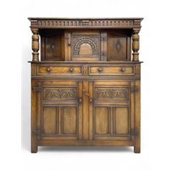 Jacobean design oak court cupboard, upper section with carved arched panelled cupboard door flanked by turned columns, beneath carved and moulded frieze, lower section fitted with two drawers over two cupboard doors with gothic arched panel decoration, raised on stile supports