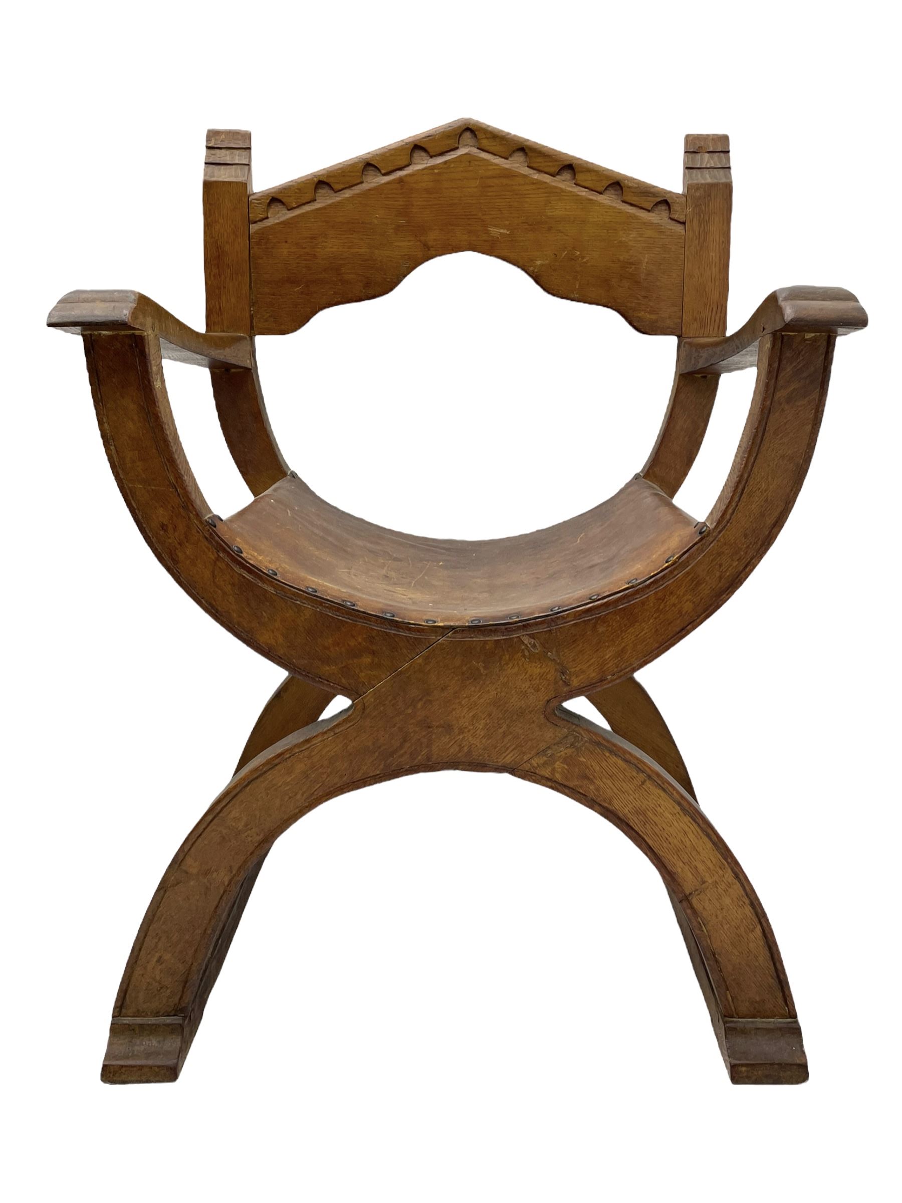 'Gnomeman' oak curved x-framed throne chair, sloped arched cresting rail carved with arcade, studded slung leather seat, the supports joined by sledge feet, rear upright carved with gnome signature, by Thomas Whittaker of Littlebeck