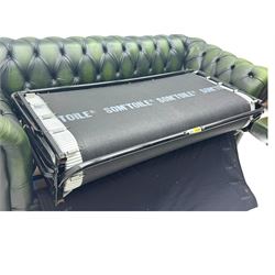 Two seat Chesterfield design sofa bed, upholstered in emerald green leather with deep-buttoned detailing, rolled arms, two loose seat cushions, and pull-out 