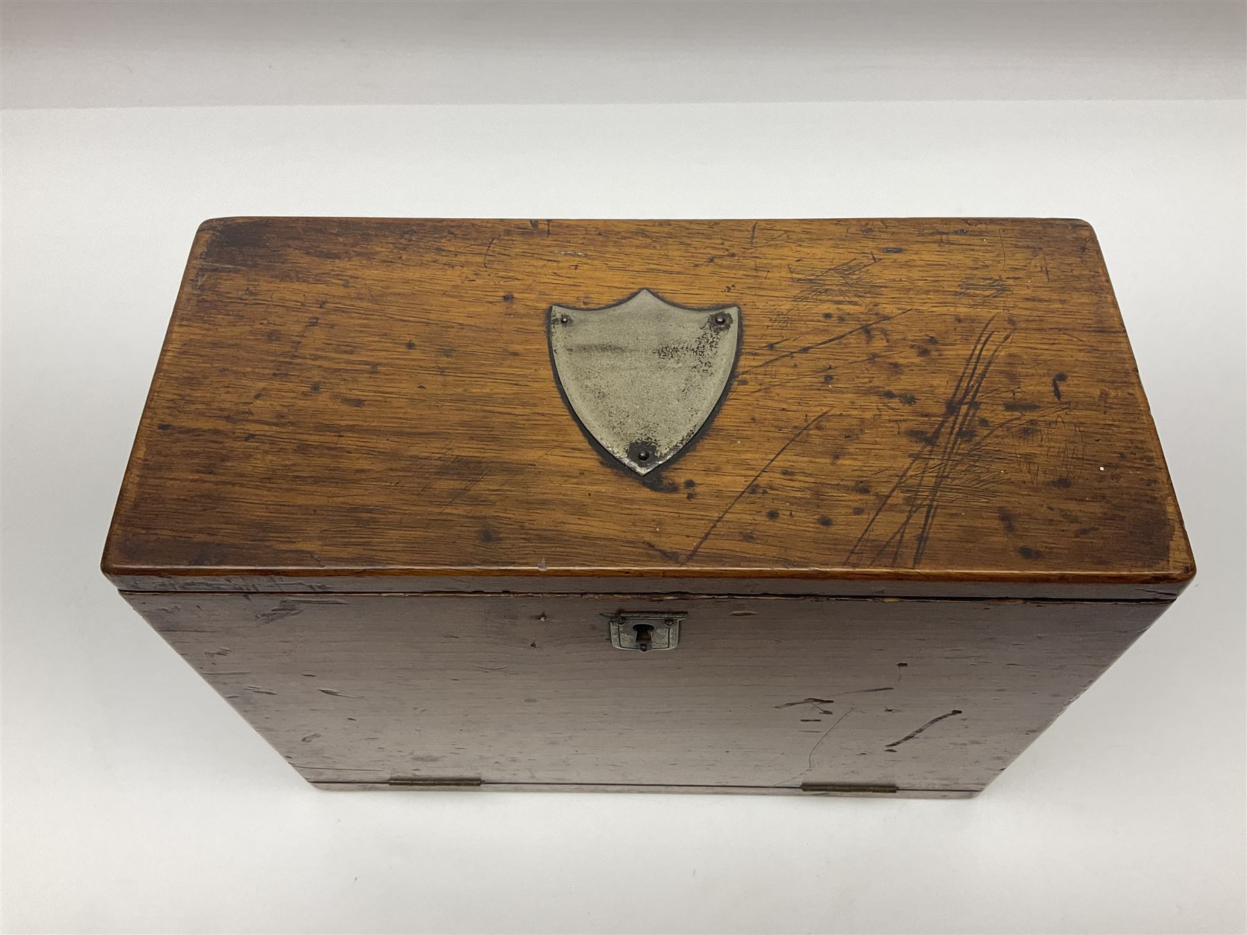 Wooden table stationery box, with drop down front and fitted interior, with metal shield plaque to the hinged lid, H18cm