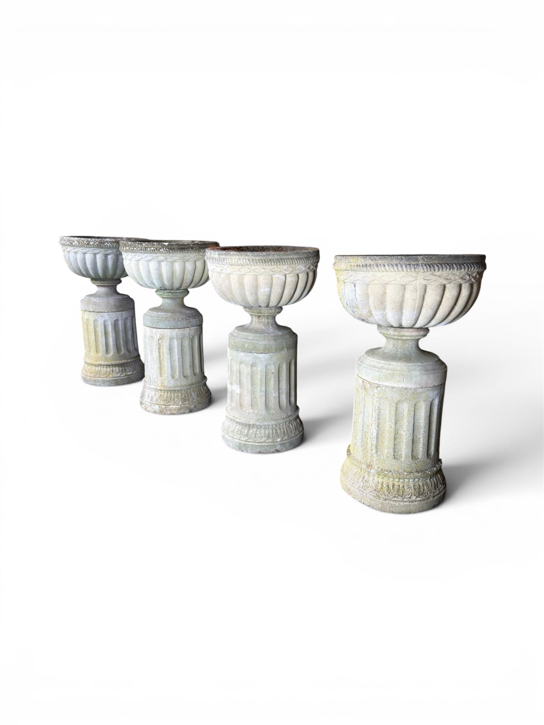 Four 20th century good quality weathered cast stone pedestal urns, circular lobed bowls with rope twist and lattice border, raised on squat base with fluted columns