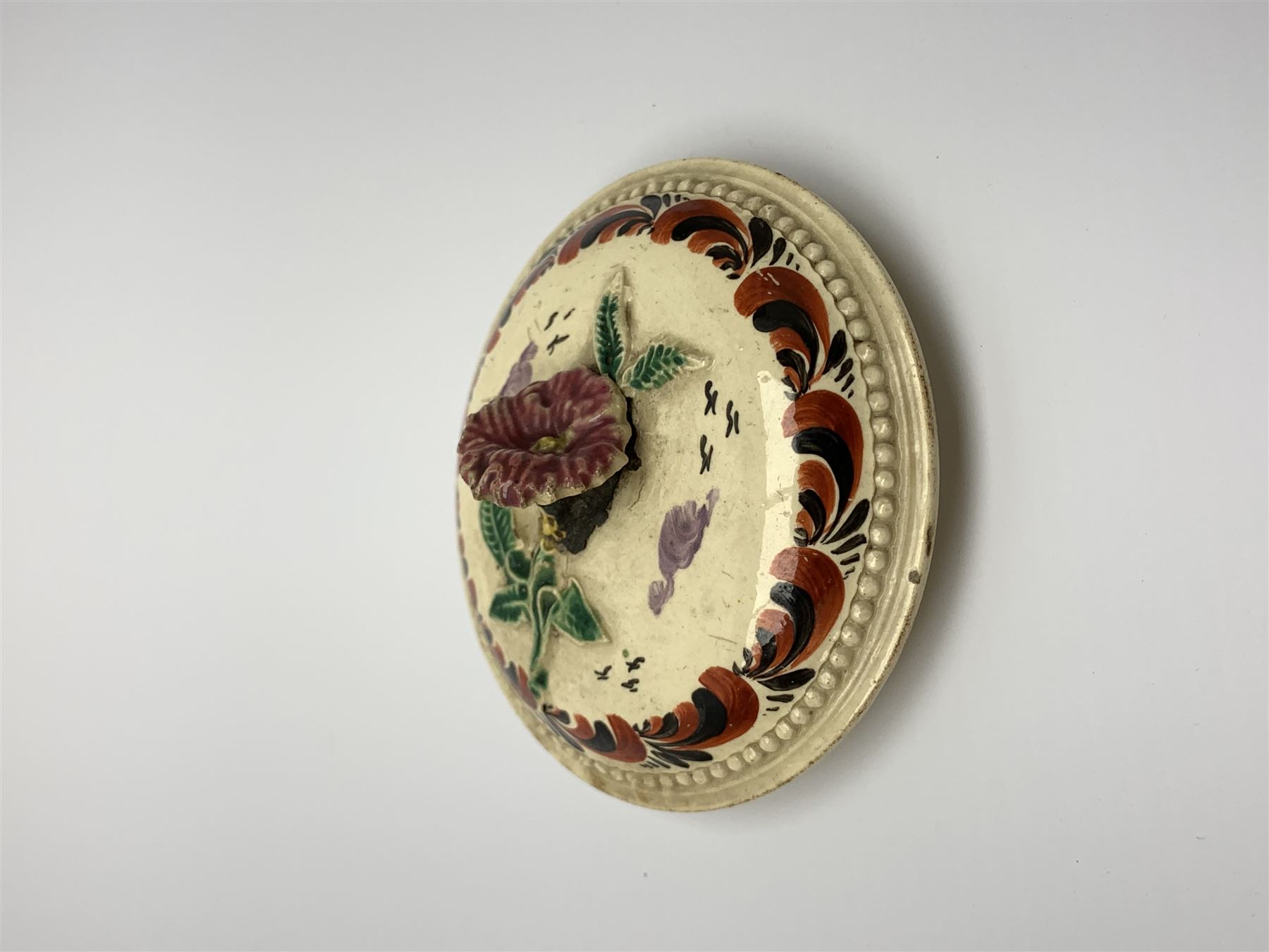 18th century creamware teapot, probably Leeds, with reeded entwined handle and floral finial to the cover, the body with hand painted polychrome decoration of figure to one side, and floral spray to the other, collectors paper label beneath inscribed Leeds Pottery, H11.5cm