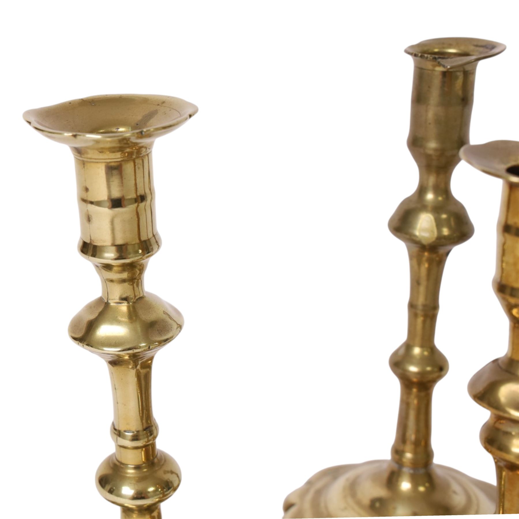pair of 18th century brass candlesticks, each having slender knopped stems and scalloped petal base, together with two other brass candlesticks, H21cm