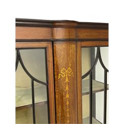 Edwardian inlaid mahogany display cabinet, enclosed by two astragal glazed doors, bowed centre inlaid with ribbon and trailing bellflowers, on square tapering supports with spade feet united by undertier 