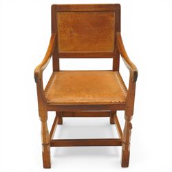Mouseman - oak panel back carver armchair, lightly adzed panel back above a tan seat with brass studded trim, flanked by swept arms raised on octagonal front supports, with carved mouse signature, by the workshop of Robert Thompson of Kilburn
