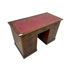 Late 19th to early 20th century walnut pedestal desk, rectangular top inset with red tooled leather writing surface, over a central frieze drawer flanked by two pedestals, each fitted with four graduated drawers with brass escutcheons and drop handles, the whole raised on a plinth base