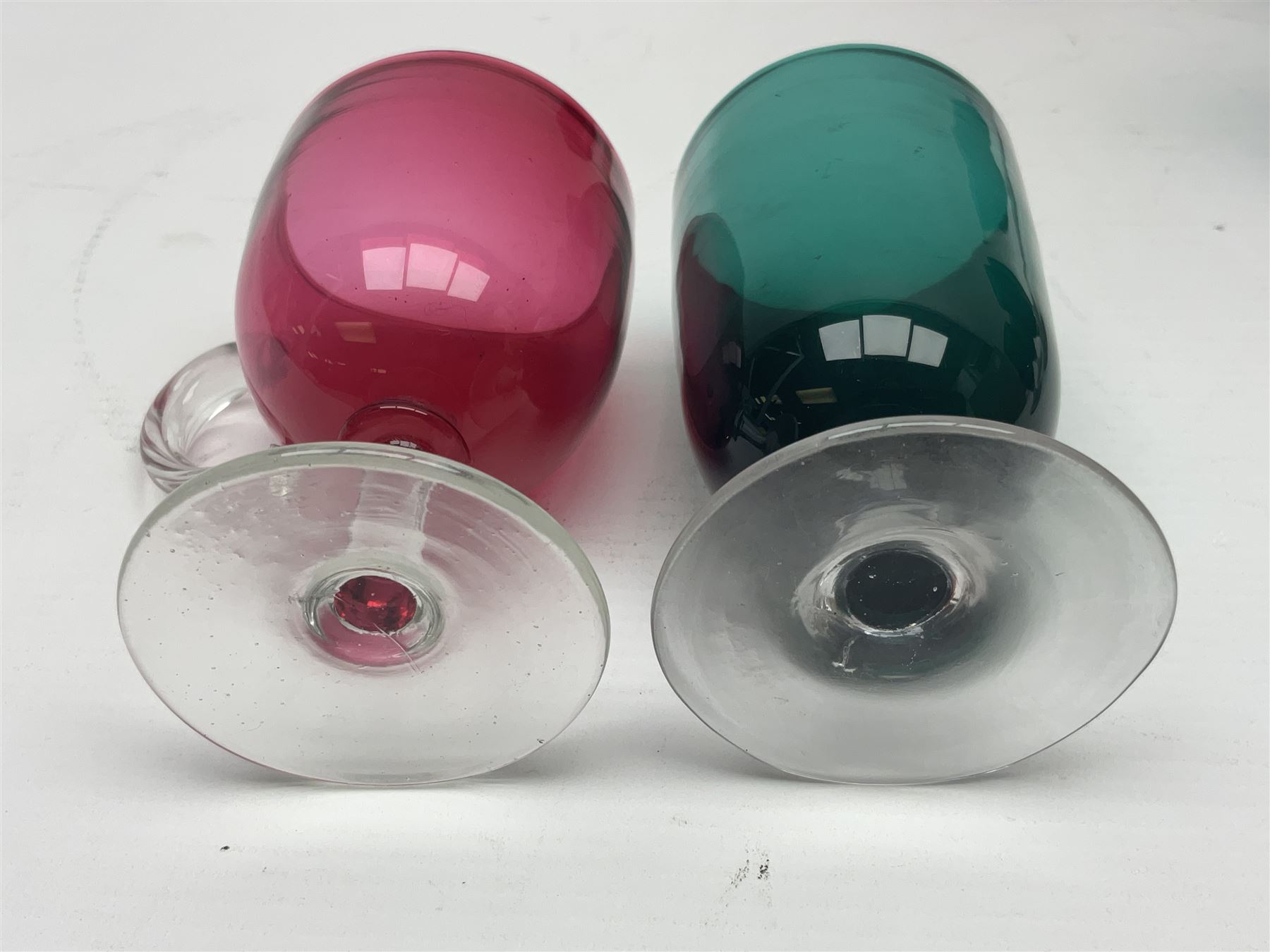 Collection of 19th century coloured glasses, to include nine cranberry glass punch cups, each with clear glass handle and foot and a set of six green glasses, with short clear stems, tallest H10cm