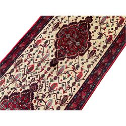 North West Persian Saveh crimson ground runner rug, the three lozenge pole medallions in an ivory field, surrounded by stylised plant motifs, the guarded border decorated with repeating geometric patterns