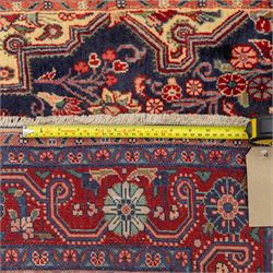 North West Persian hand-knotted Sarouk rug, central navy ground field with cusped lozenge medallion with pendant motifs, scrolling palmettes, and floral sprays, cream spandrels, and madder red border of stylized rosettes and leafy meandering vines between multiple guard stripes 