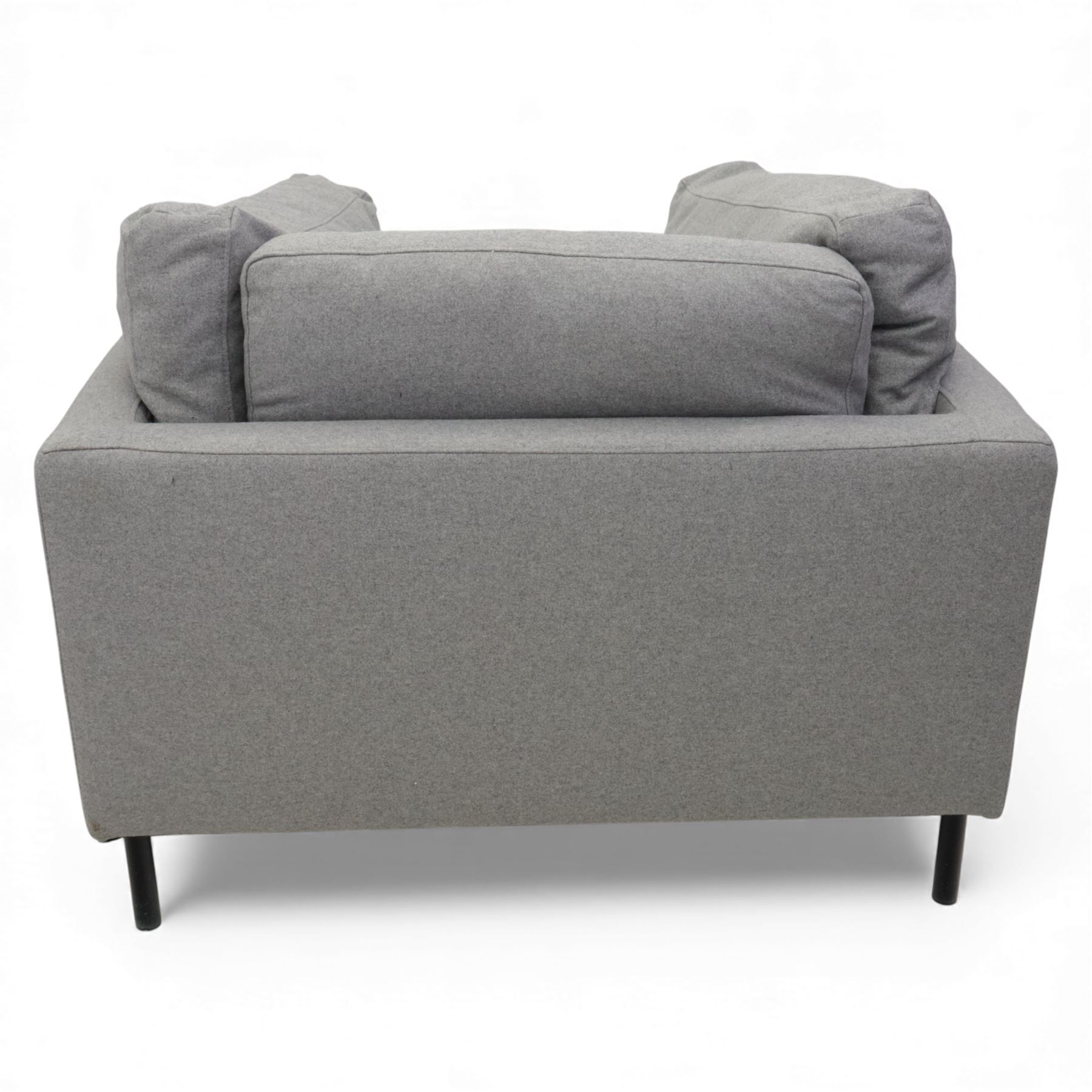 Modern snuggler armchair, upholstered in grey fabric, box-shaped frame with loose back and side cushions, raised on slender black metal legs