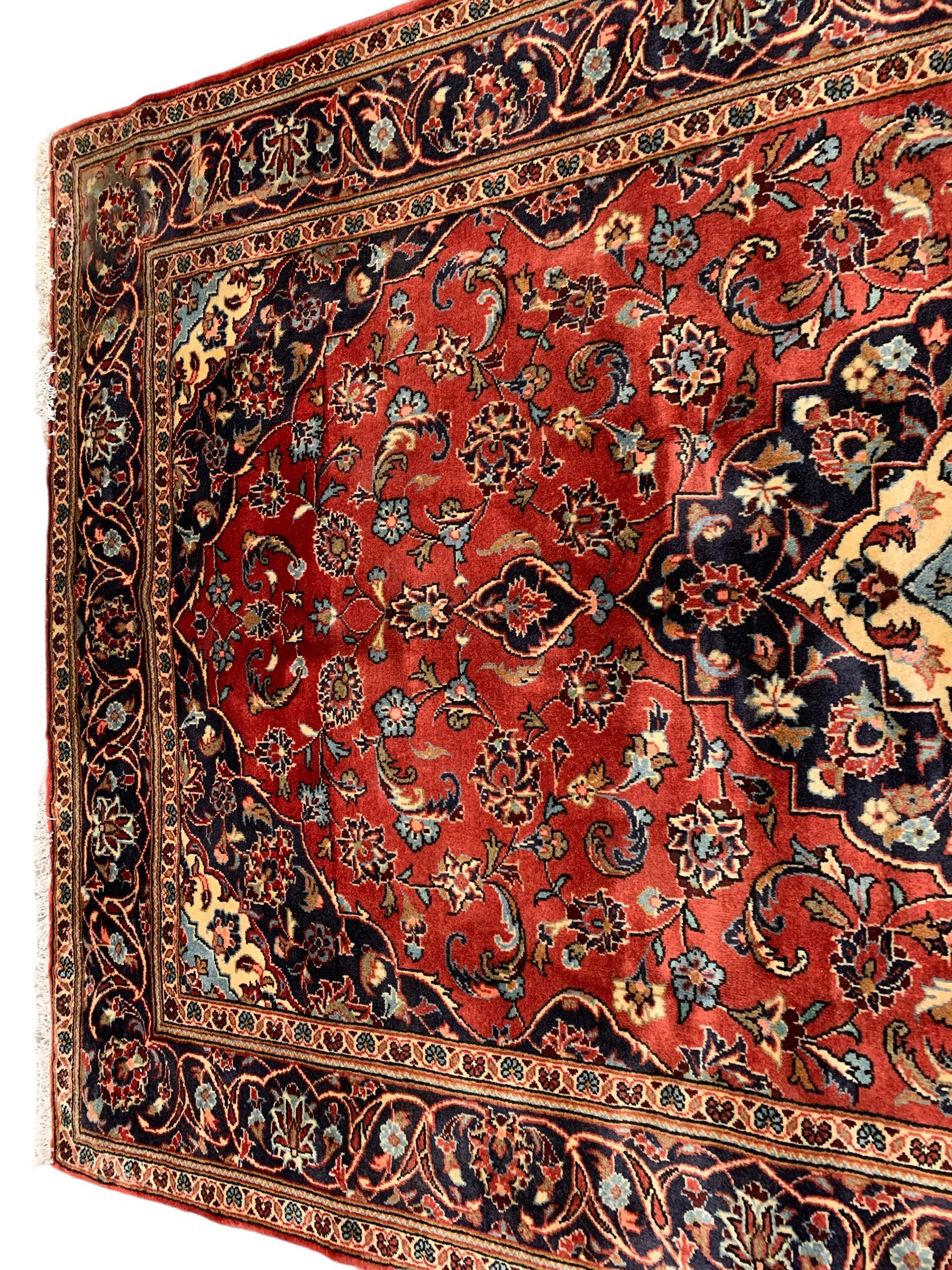 Persian Ardakan crimson ground rug, the field with shaped floral design medallion surrounded by curled leafy branches, scrolling border with stylised plant motifs