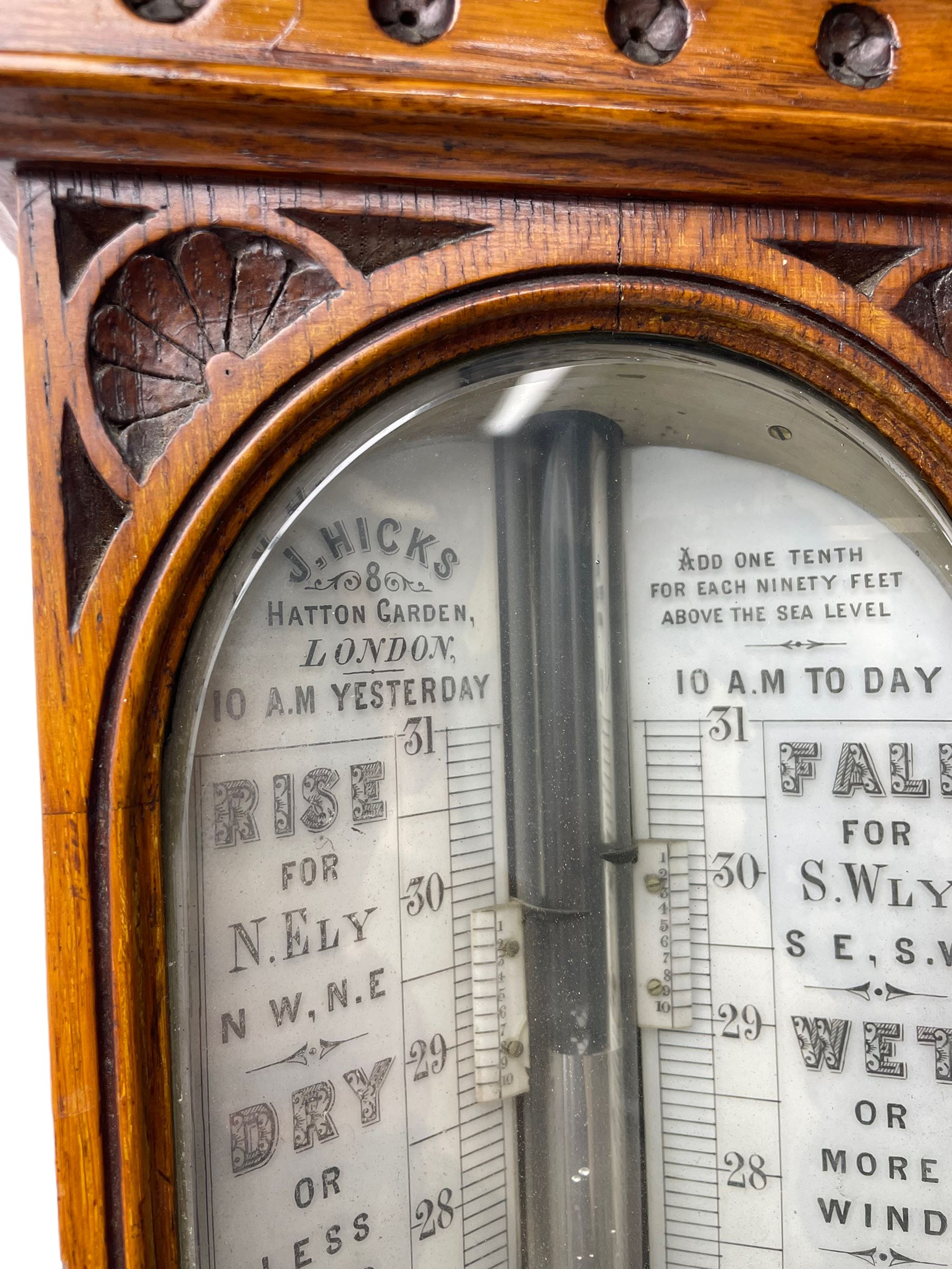 J Hicks - Hatton Garden London, - late 19th century carved oak cased Fitzroy barometer in a richly carved case with a carved crested pediment and square cistern cover, inverted opaline register reflecting FitzRoy's predictions and a scale from 27 to 31 inches of barometric pressure, with a thick bore cistern tube and adjustable rack and pinion twin vernier, fitted with a glazed snail bulb mercury thermometer recording the air temperature in both Fahrenheit and Celsius. Mercury clean and present.
James Joseph Hicks was born in Ireland, however, early in his life he moved to London where he was apprenticed to the instrument maker Louis P Casella. In 1860 he went into business in his own right as a scientific instrument maker at 8 Hatton Gardens. In 1864 he was granted membership to the British Meteorological Society and exhibited instruments at the Royal Society Exhibitions between 1876 and 1913. Hicks was one of London's most prolific and eminent barometer makers. 