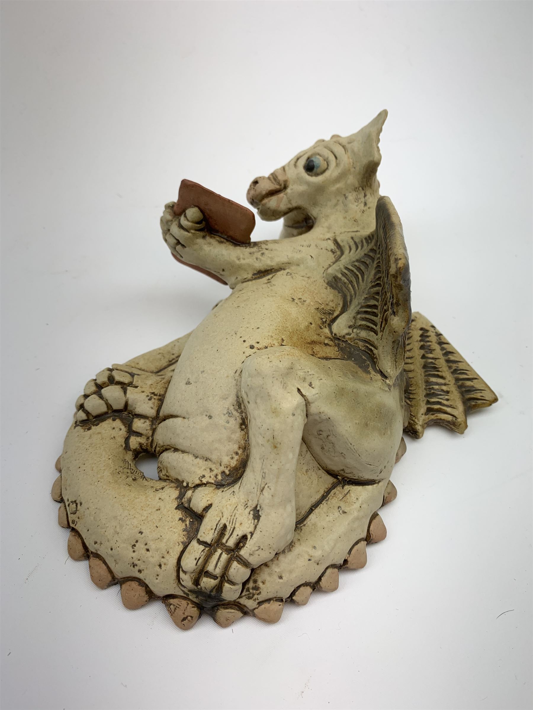 Zell Osbourne (British, Contemporary), Bookworm, a Studio Pottery figure modelled as a recumbent dragon with book, L21cm. 