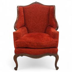 19th century Rococo revival upholstered armchair, red textured fabric over a carved walnut frame, shaped back and sides, floral carved serpentine seat rail, on cabriole supports 