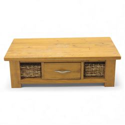 Contemporary pine coffee table, rectangular planked top with moulded edge, fitted with a central drawer to either side with brushed metal handle, flanked by two open compartments housing wicker basket drawers, plain sides, raised on square block feet