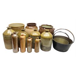 Quantity of stoneware flagons, to include Skipton, Clitheroe and Hellifield related examples, four salt glazed bottles, large cylindrical stoneware jar, large twin handled jar and vase, together with two brass jam pans, tallest H35cm