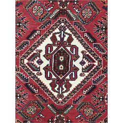 Persian Qashqai crimson ground runner, the central field decorated with three large geometric medallions with intricate angular and floral motifs, the indigo spandrels with complementary geometric designs, bordered by an ivory band with repeating floral patterns and angular vines
