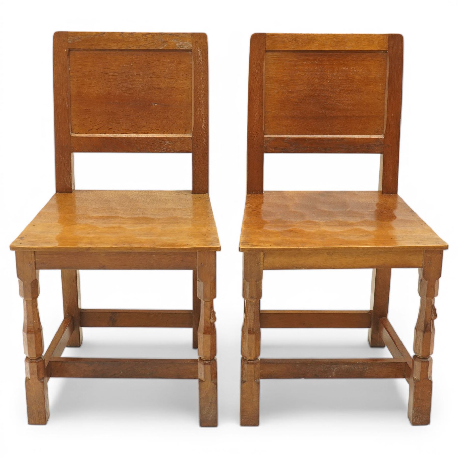 Mouseman - pair of oak panel back side chairs, adzed panel back and seat, on octagonal supports, with carved mouse signature, by the workshop of Robert Thompson of Kilburn