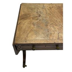 Regency mahogany sofa table, canted rectangular drop leaf top with walnut crossbanding, fitted with two frieze drawers with central lozenge decoration, two opposing false drawers, vasiform end supports with reeded edge and central roundel joined by ring turned and reeded stretcher, splayed supports on scaled brass cups and castors