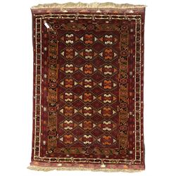 Persian maroon ground rug, the field decorated with interconnected lozenges, geometric design border decorated with stylised plant motifs