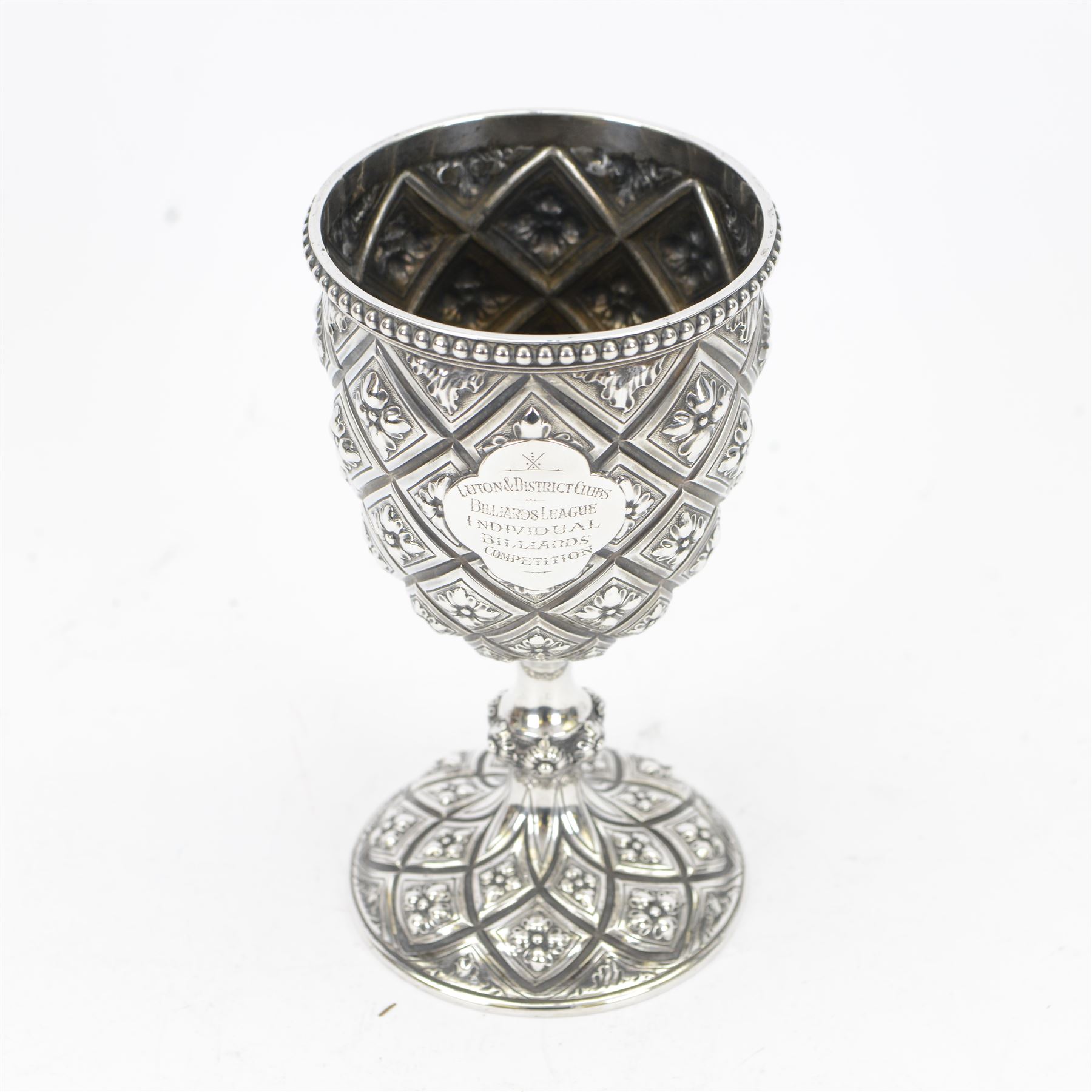 Victorian silver trophy cup or goblet, the cup with personally engraved quatrefoil panel and beaded rim, upon a knopped flower head detailed stem and spreading circular foot, embossed throughout with a flower head diamond trellis pattern, hallmarked Robert Hennell III, London 1860, H18cm