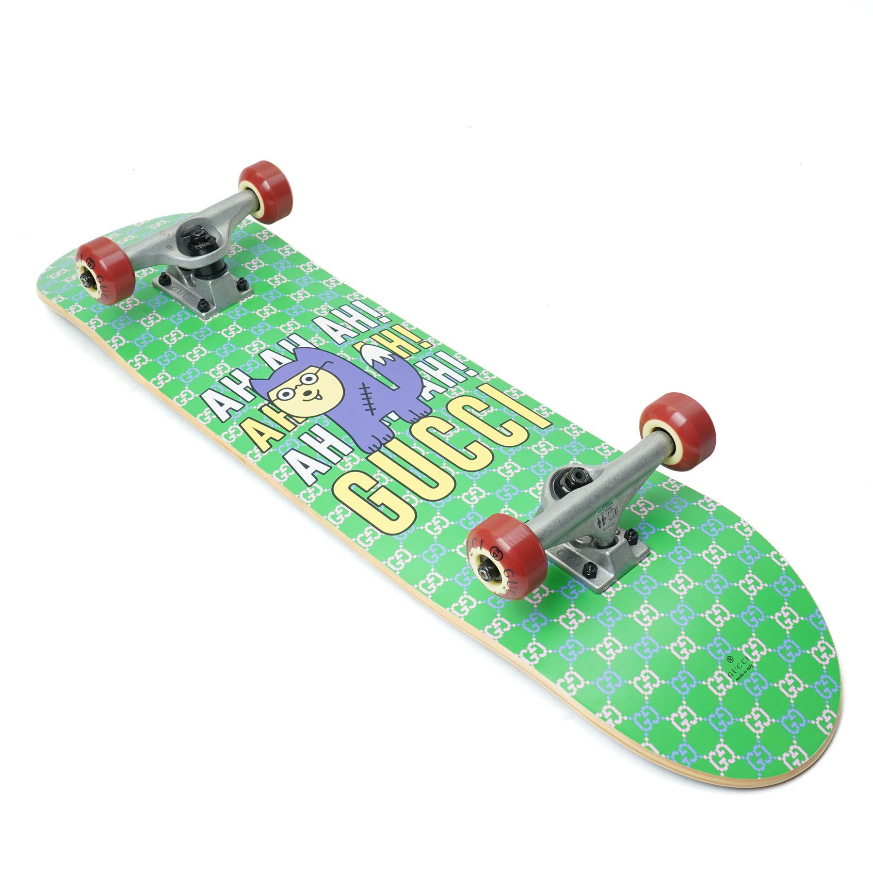 Gucci x Palace skateboard, Spring/Summer 2021, green GG monogram wood deck with multicolour ‘AH AH AH! GUCCI’ lettering and cartoon character mascot motif, fitted with Gucci-branded metal trucks and red and cream wheels, model no. 689103 JCGMN, presented with original GG monogram drawstring dust bag, protective sleeve, outer box and accompanying cards, Skateboard L81cm W20cm