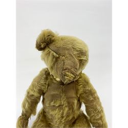 Early 20th century English teddy bear, with wood wool filled body with jointed limbs, felt covered paw pads, five claw stitching to feet and elongated arms with spoon shaped paws H14