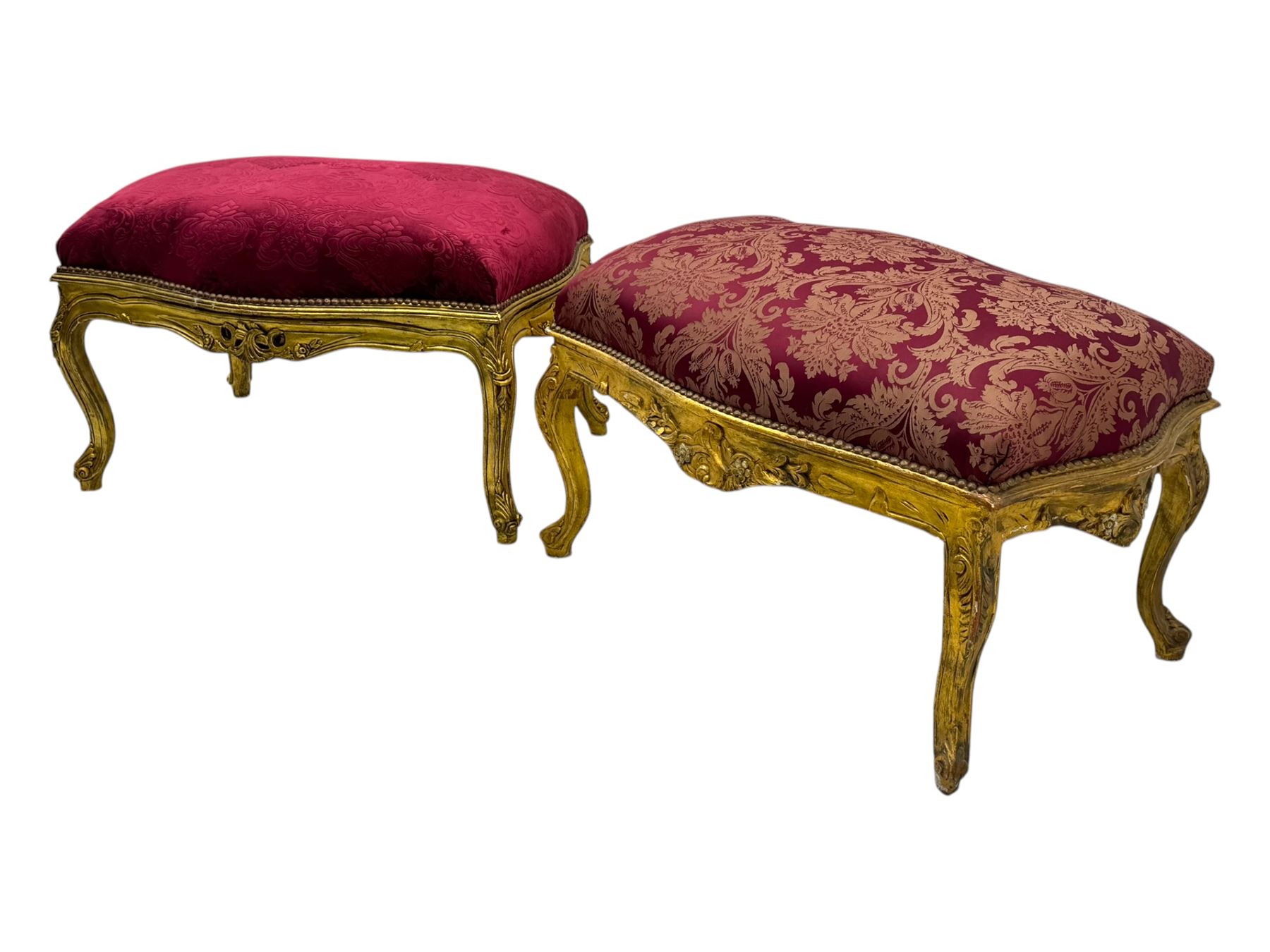 Pair of Louis XV-design giltwood stools, each upholstered in red damask fabric with slight variations in patterns, the carved frames adorned with scrolling foliage and shell motifs, raised on cabriole supports