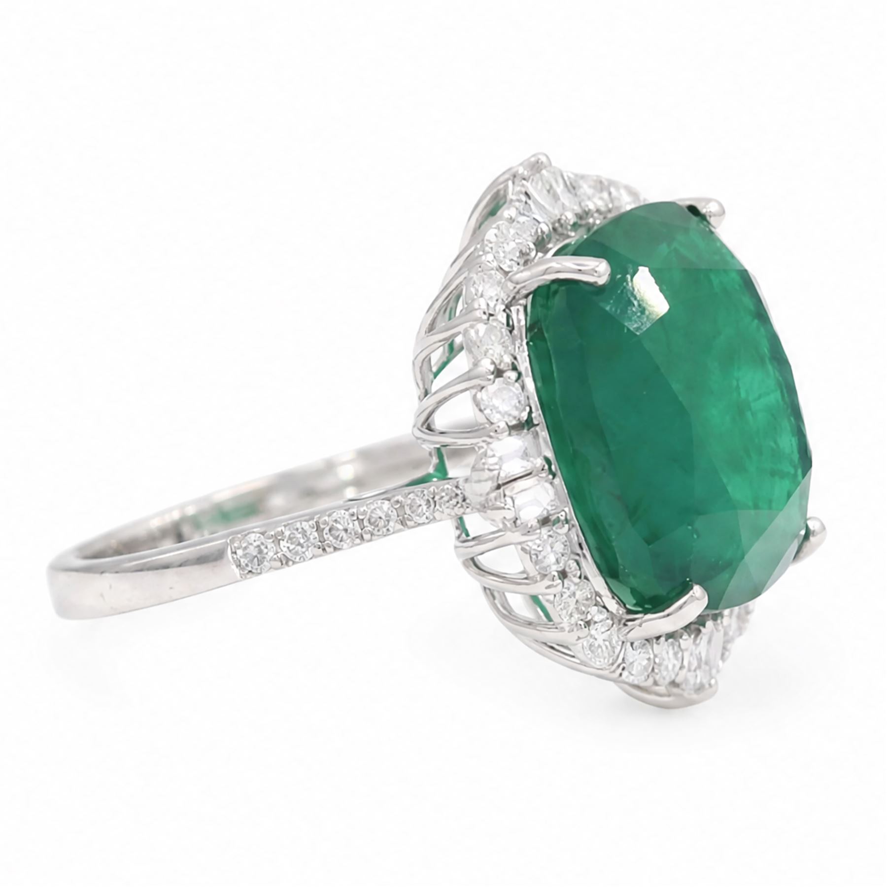 18ct white gold emerald and diamond cluster ring, single cushion cut emerald of approx 13.20 carat, surrounded by round brilliant and baguette cut diamonds and diamond set shoulders, stamped 18K, total diamond weight approx 1.00 carat
