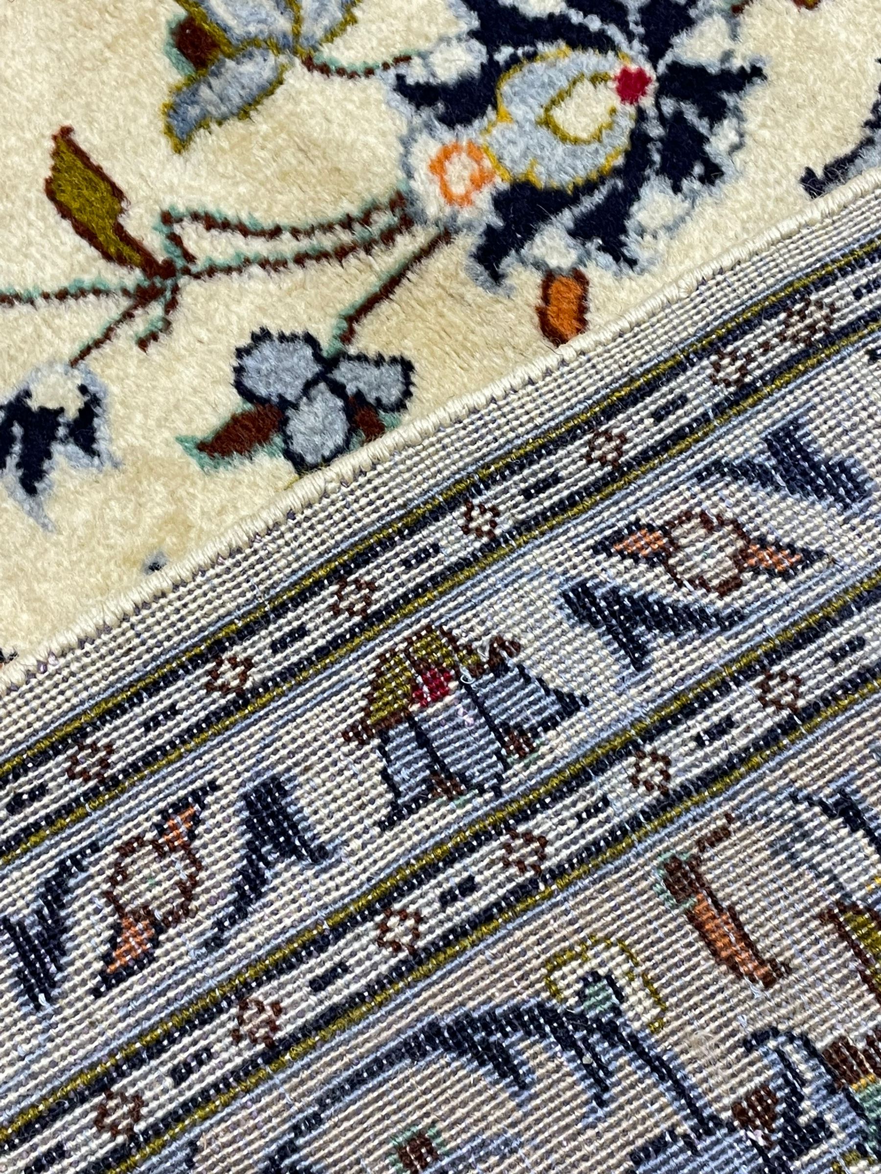 Persian Kashan ivory ground carpet, decorated all-over with interlacing foliate and stylised plant motifs, central scrolling medallion and matching spandrels, the guarded border decorated with repeating palmettes