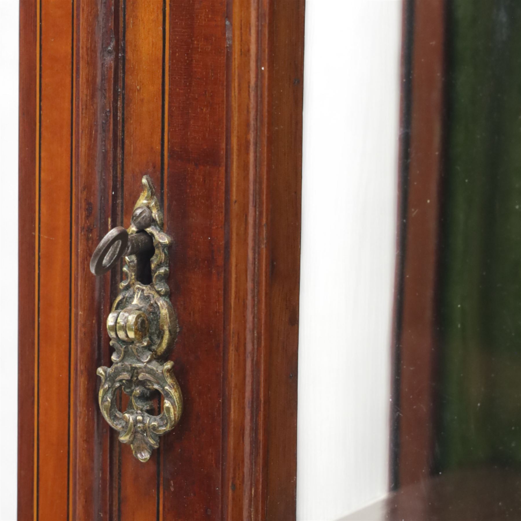 Edwardian inlaid mahogany display cabinet, the moulded cornice above an astragal glazed door enclosing two baize lined shelves, the lower section with a panelled cupboard door, raised on square tapering supports