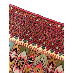 Turkaman red ground rug, the field divided into horizontal rows and decorated with geometric motifs, intricately pattern borders and end panels