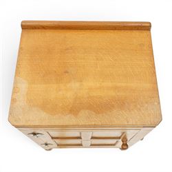 Mouseman - adzed and panelled oak bedside cupboard of small proportions, raised back over rectangular canted top, fitted with single panelled cupboard door with chamfered rails and turned knob handle, enclosing single shelf, raised on octagonal feet,  carved with mouse signature, by the workshop of Robert Thompson of Kilburn