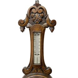 English - Edwardian aneroid barometer in a carved scroll work oak case, with a mercury box thermometer recording room temperature in degrees Fahrenheit and Celsius, circular  porcelain register written in gothic script with weather predictions and barometric air pressure from 26 to 31 inches, steel indicating hand and brass recording hand.