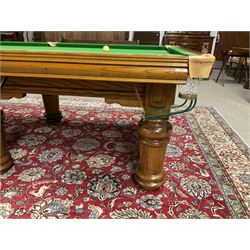 Late 20th century oak slate bed billiard table, on six turned column supports,  together with cues, ball set, baize brush, triangles and scoreboard 