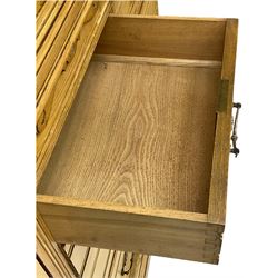 Late 19th century ash combination wardrobe, projecting cornice over foliage carved frieze, the left-hand upright enclosed by mirror glazed door, the right-hand side fitted with double panelled cupboard over two short and three long drawers, the upper panels carved with curled leaves and central scroll cartouche, on bracketed plinth 