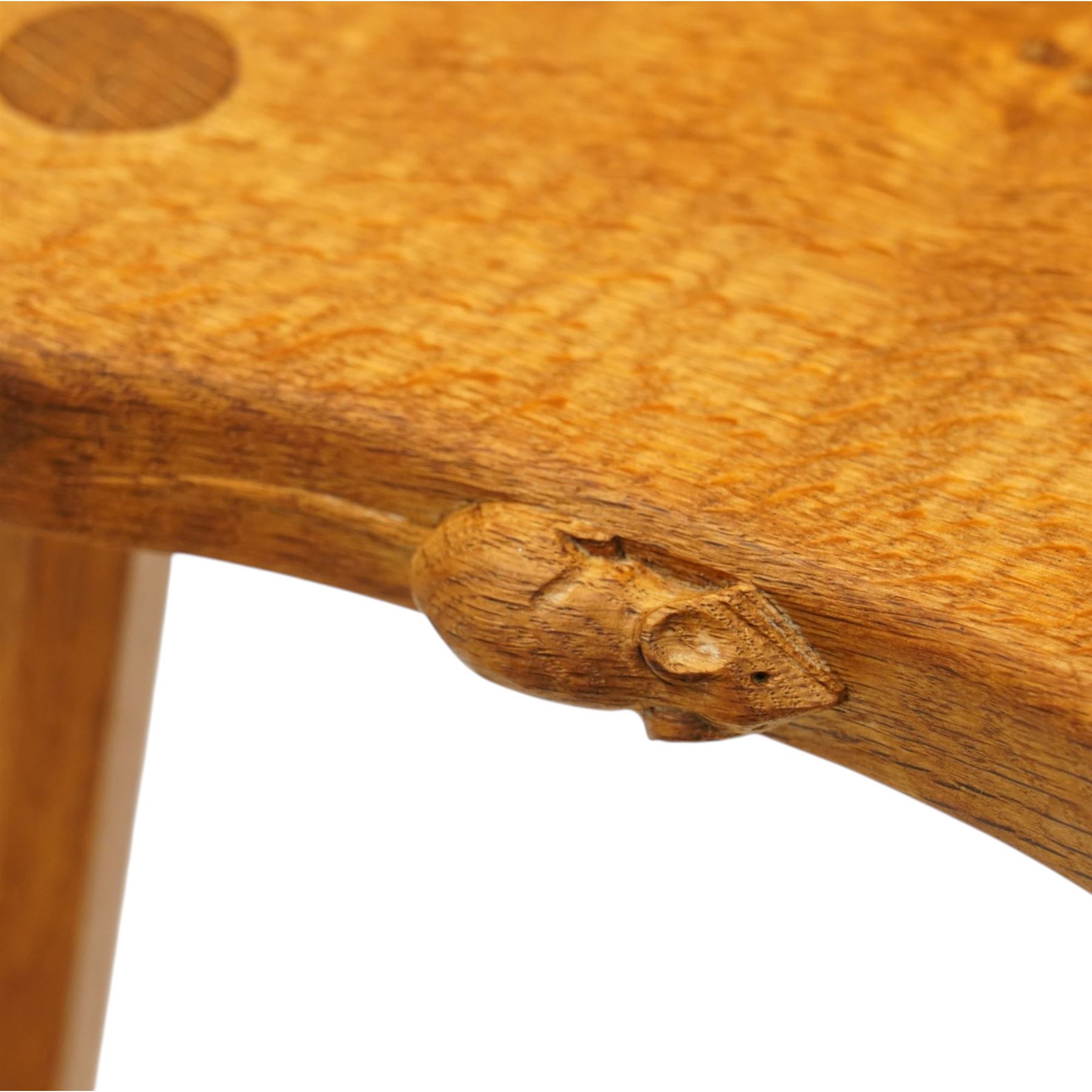 Mouseman - oak three-legged stool, dished kidney-shaped seat with burr inclusions, raised on three octagonal splayed supports, with carved mouse signature, by the workshop of Robert Thompson of Kilburn