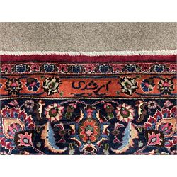 Persian Meshed carpet, plum ground and decorated with stylised flower heads and interlacing foliate, large central stylised medallion with orange detail, the orange mirrored in the five band border decorated with scrolling floral design, signature panel to end 