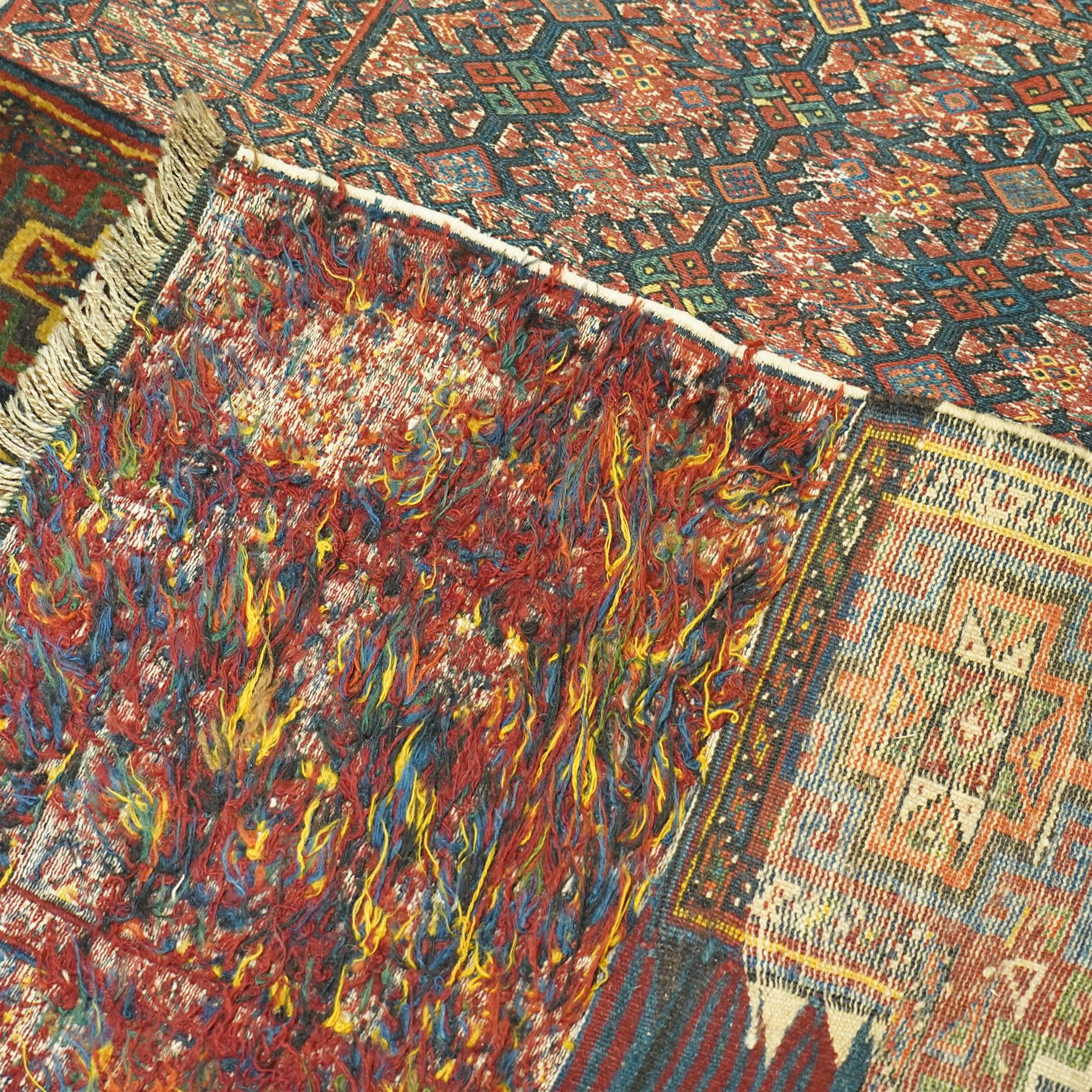 Central Asian vintage saddle cover, probably Turkmen, wool pile and flatweave on wool foundation, decorated with geometric tribal motifs in a palette of madder red, indigo, ivory, and dark brown, with cotton fringe ends 