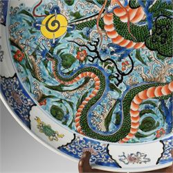 Chinese charger, decorated in blue, green and red enamels with a four clawed dragon chasing the flaming pearl amidst waves and flower heads, the rim with border of alternating reserves of auspicious emblems and flower scrolls, bearing apocryphal Kangxi mark beneath, D38cm 

