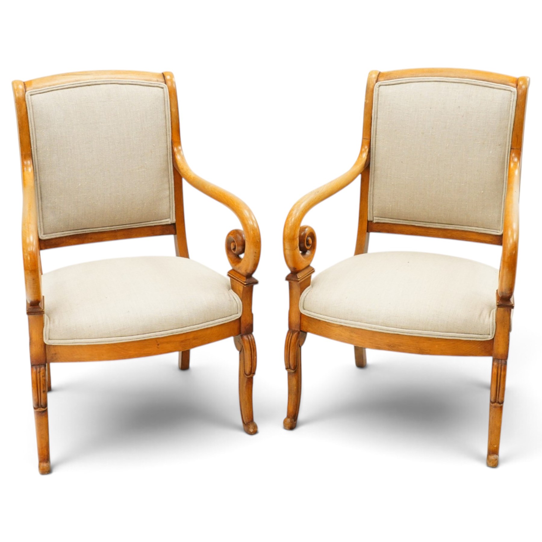 Pair of French Empire design fauteuil armchairs, high back over scrolled arm terminals, upholstered in cream fabric, on scroll carved cabriole supports
