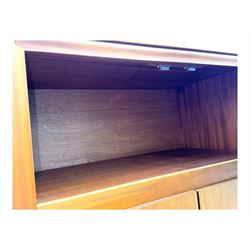 William Lawrence - mid-20th century teak double wardrobe, upper storage section over twin doors featuring recessed handles and contrasting horizontal panel, enclosing hanging rail compartment, towel rail, mirror, shelves and drawer, on plinth base with concealed castors