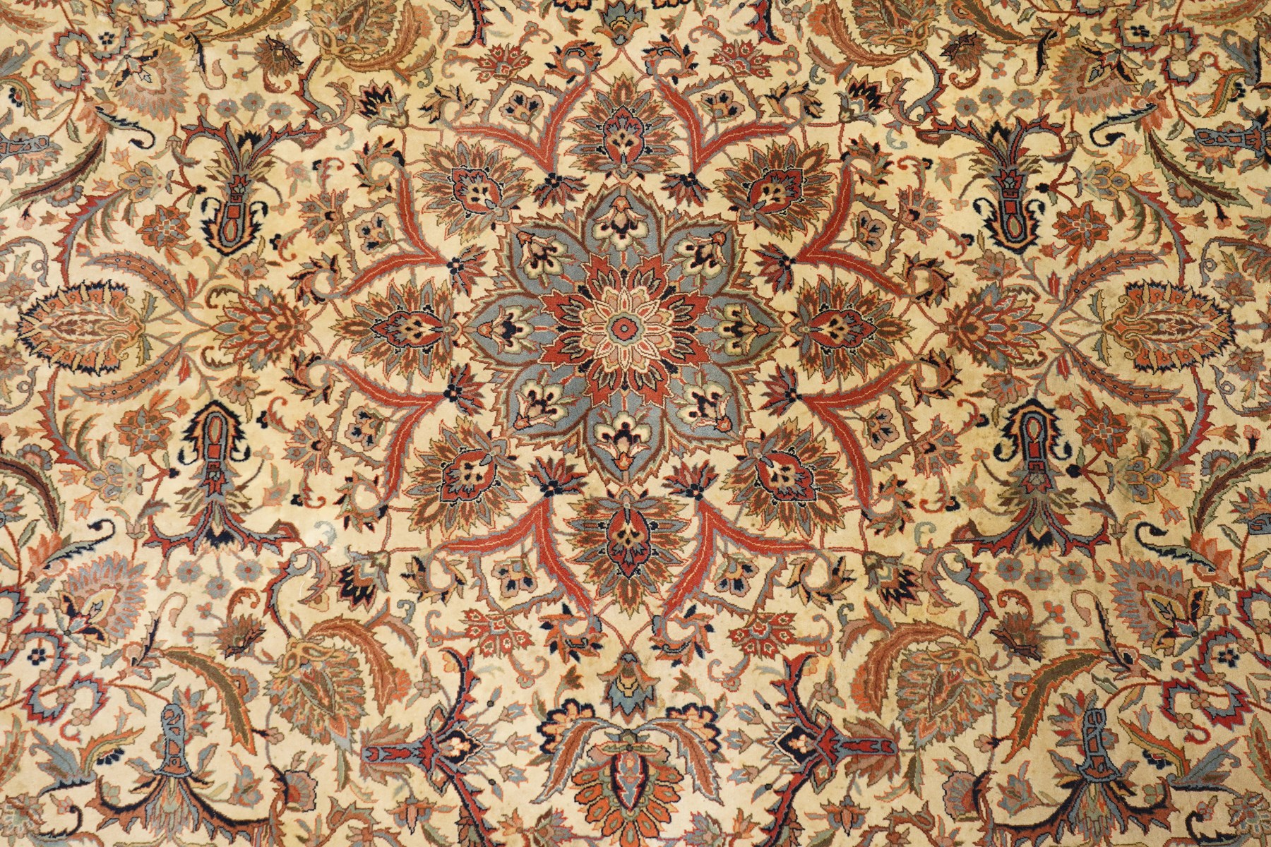 Persian Isfahan ivory and crimson ground rug, the busy field with central floral pole medallion surrounded by foliate motifs and stylised palmettes, the indigo guard line with repeating scrolling plant motifs