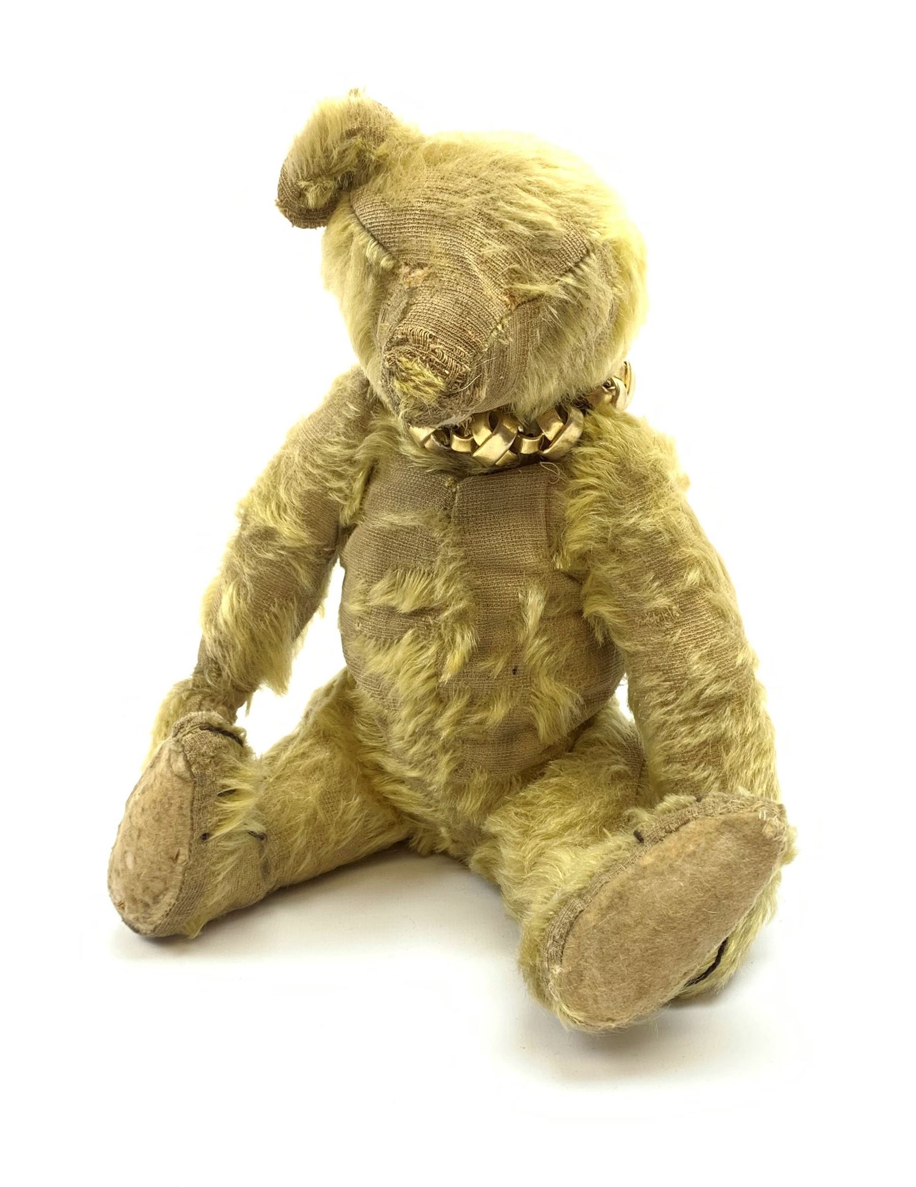 Early 20th century English teddy bear, with wood wool filled body with jointed limbs, felt covered paw pads, five claw stitching to feet and elongated arms with spoon shaped paws H14
