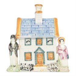 19th Century Staffordshire pearlware Prattware type money box, modelled as a houe with two figures to the front corners, H13cm