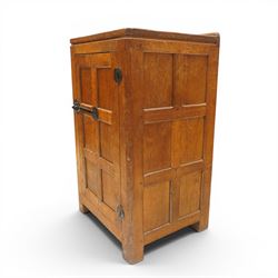 Mouseman - early-to-mid-20th century adzed and panelled dark oak bedside cupboard, raised back over rectangular canted top, fitted with single panelled cupboard door with chamfered rails and wrought iron fittings, enclosing two adjustable shelves, raised on canted square feet, carved with mouse signature, by the workshop of Robert Thompson of Kilburn