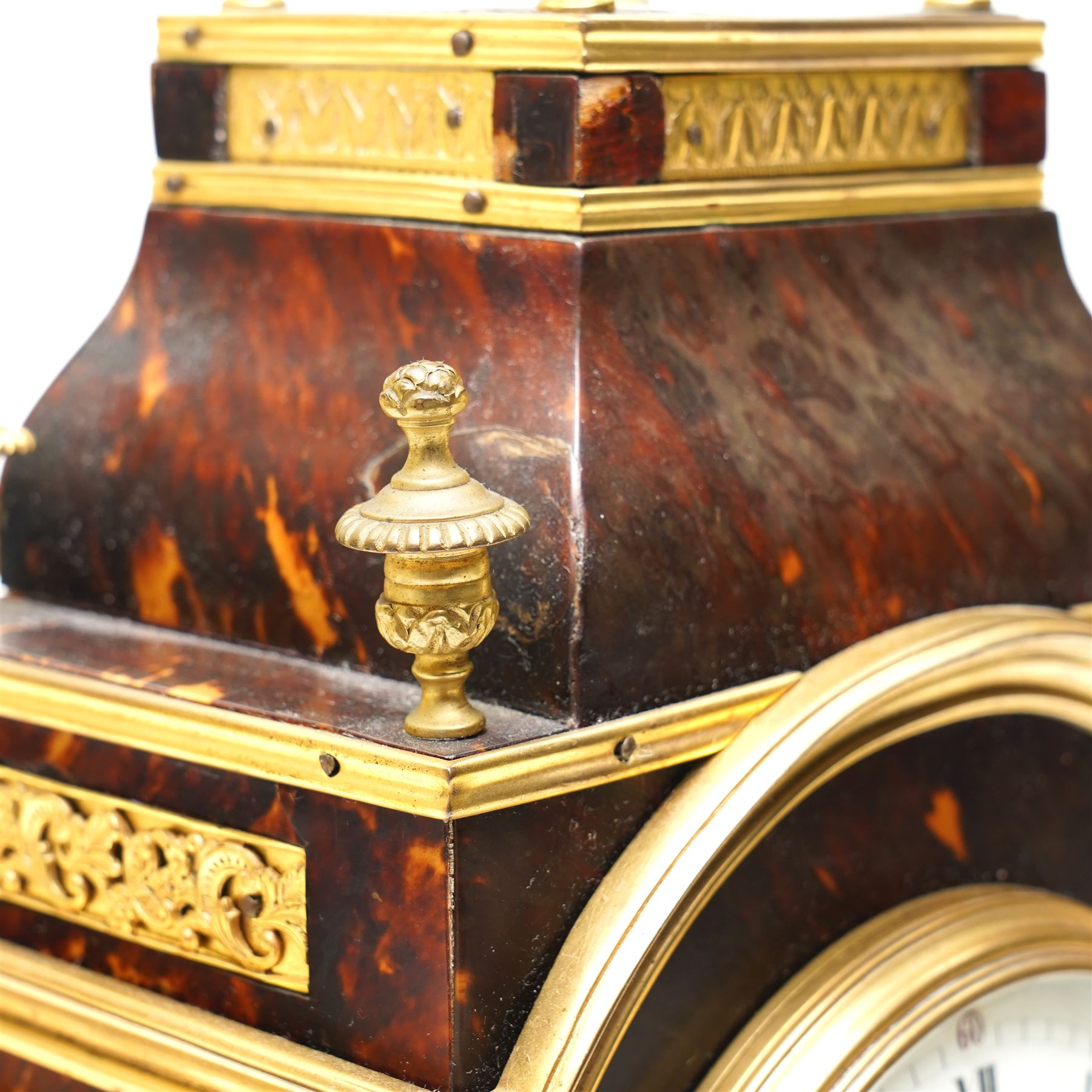 French-late 19th century brown stained 8-day faux Tortoise shell and ormolu mounted mantle clock, rectangular case with glazed side panels and shaped pediment with matching finials, convex enamel dial with Roman numerals, minute track and steel moon hands within a cast brass glazed dial bezel,
twin barrel movement with rack striking, striking the hours and half hour on a coiled gong. With pendulum and key.