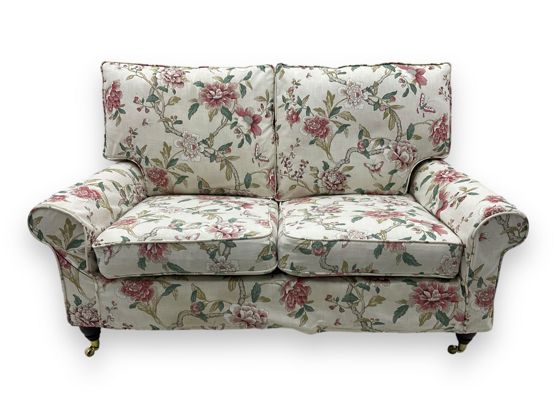 Steed Upholstery - 'Knightsbridge' two seater sofa, upholstered in cream fabric with pink and green floral design, loose back and seat cushions, raised on mahogany supports with brass castors
