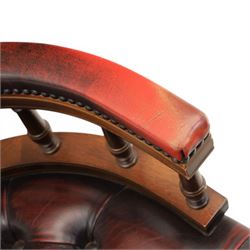 Captains swivel desk chair upholstered in oxblood leather, buttoned back and seat, shaped arm bow raised on turned spindles, five spoke base raised on castors